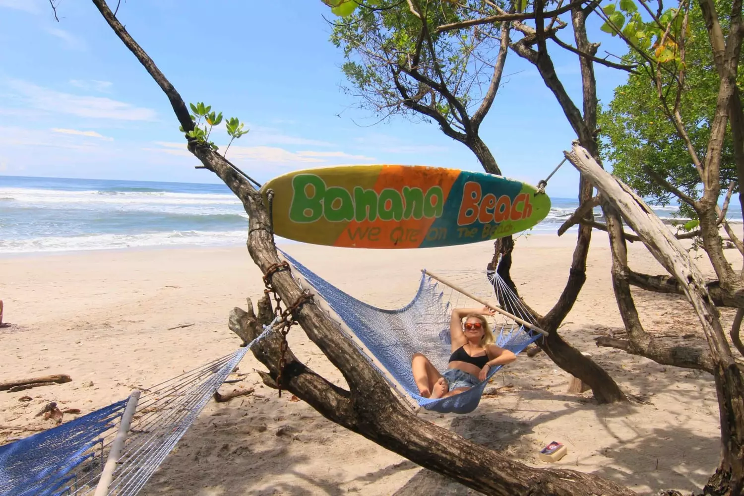 Girl in hammock on beach with surfingboard