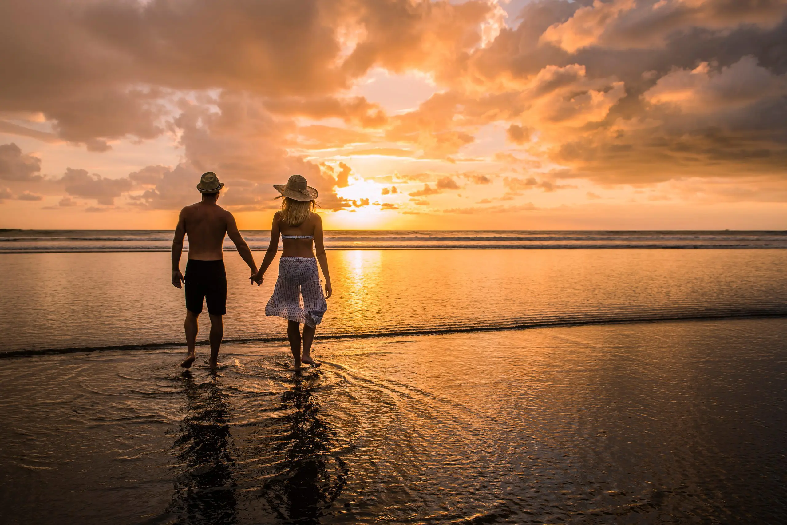 Couple waling hand in hand in the sunset on a a beach